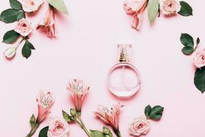 aux femmes parfum bouteille et des roses fleurs sur rose Contexte. Créatif mise en page, copie espace photo