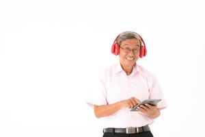Senior homme asiatique heureux d'écouter de la musique en ligne avec un casque et une tablette, isolé