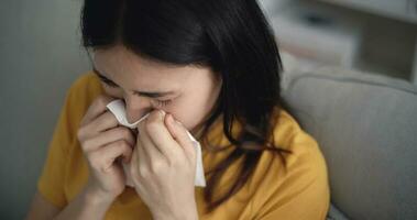 asiatique Jeune femme fièvre éternuement dans soufflant sa nez dans papier tissu à Accueil photo