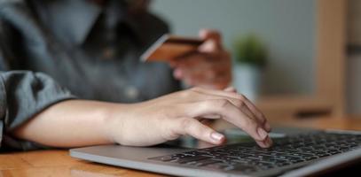 femme main tenant la carte de crédit avec l'utilisation d'un ordinateur portable pour les achats en ligne tout en passant des commandes à la maison. affaires, style de vie, technologie, commerce électronique, banque numérique et concept de paiement en ligne. photo