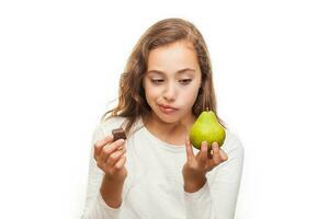 Jeune fille choisir entre fruit et Chocolat isolé sur blanc Contexte photo