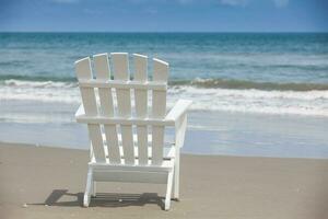 vide blanc en bois chaise à une paradisiaque plage sur le tropiques dans une magnifique ensoleillé journée photo