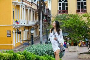 magnifique femme sur blanc robe en marchant seul à le des murs alentours de le colonial ville de Carthagène de Indes photo