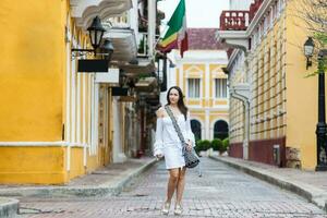 magnifique femme sur blanc robe en marchant seul à le des rues de le colonial fortifiée ville de Carthagène de Indes photo