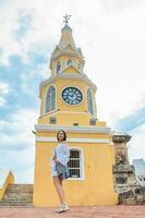 magnifique femme en marchant autour Carthagène de Indes suivant à le célèbre l'horloge la tour photo