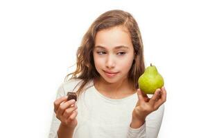 Jeune fille choisir entre fruit et Chocolat isolé sur blanc Contexte photo