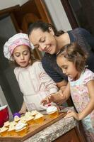 mère et filles ayant amusement dans le cuisine cuisson ensemble. en train de préparer petits gâteaux avec maman photo