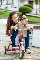 magnifique Jeune mère en jouant avec sa un année vieux bébé en plein air. avec maman équitation mon tricycle photo