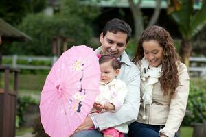 Jeune Parents ayant amusement en plein air avec leur un année vieux bébé fille. bonheur concept. famille concept photo