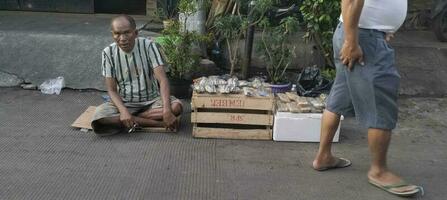 une rue vendeur est attendre pour les clients qui volonté acheter le sien marchandises. jakarta mai 1, 2023 photo