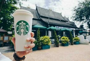 chiang Mai, Thaïlande- 24-juillet-2017 - Quelqu'un montrant une tasse de venti Taille Starbucks chaud café dans de face de de Starbucks lanna style de chiang mai le nord Province de Thaïlande. photo