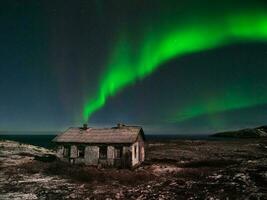 un vieux abandonné maison en dessous de le nord étoilé ciel. nuit polaire paysage avec le aurore borealis photo