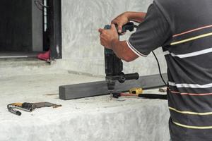 Mise au point sélective sur les mains du travailleur tenir la machine de forage pendant le forage sur le sol en ciment sur le chantier de construction photo