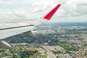 Gros plan aile d'avion en volant dans les airs avec paysage urbain ci-dessous photo