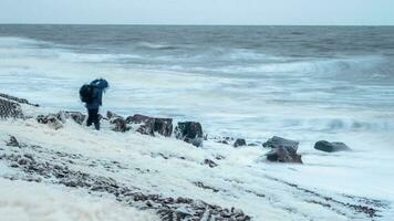 figure de une homme avec une sac à dos dans une brouiller dans une fort vent dans une tempête. blanc mer côte. spectaculaire nord paysage photo