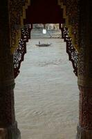 une passager bateau sur le rivière dans une Cadre cette pairs en dehors entre le piliers de le temple photo