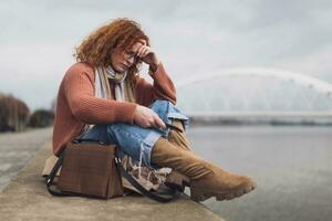 dérangé Jeune femme avec taches de rousseur et frisé gingembre cheveux en plein air photo