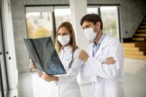 deux médecins masqués examinant une radiographie