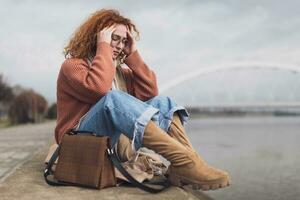 dérangé Jeune femme avec taches de rousseur et frisé gingembre cheveux en plein air photo