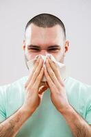 une homme avec vert T-shirt soufflant le sien nez photo