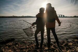 père et fils sont pêche sur ensoleillé hiver journée photo