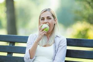 une femme en mangeant un Pomme sur le parc photo