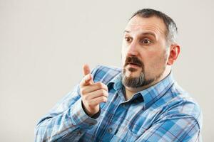 une homme avec une bleu plaid chemise fabrication une visage photo