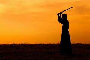 silhouette de kendo combattant avec shinaï plus de le le coucher du soleil photo