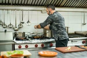 une chef est en train de préparer une repas dans le Restaurants cuisine. photo