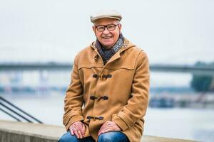 Extérieur portrait de une content Sénior homme dans hiver manteau photo