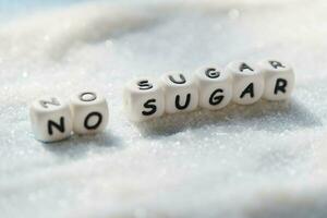 non sucre texte blocs avec blanc sucre sur en bois arrière-plan, suggérant suivre un régime et manger Moins sucre pour santé photo