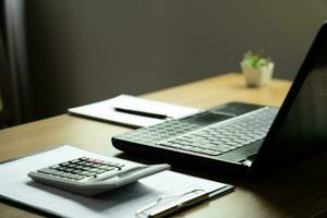 en bois bureau avec portable et documents, livres et calculatrices, bureau Contexte et affaires concept photo