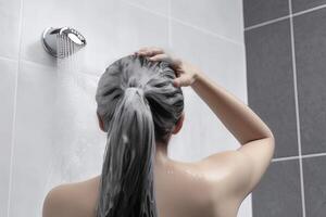 femme la lessive cheveux avec shampooing et douche dans le salle de bains. ai généré photo