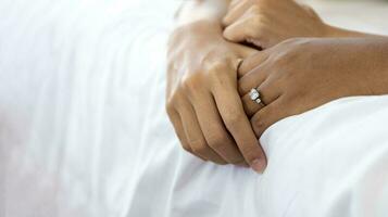 proche en haut main de mari et épouse en portant ensemble sur le lit avec mariage diamant bague sur sa doigt pour aimer, sensuel, romance et intimité relation concept photo
