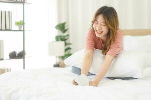 portrait Jeune adulte asiatique femme séance sur lit avec content visage après réveiller en haut dans Matin photo