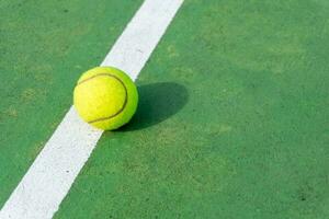 Jaune tennis Balle sur vert tribunal et blanc lignes. Haut angle vue de tennis Balle sur rechercher. photo