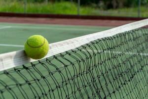 proche en haut de tennis Balle clips le Haut de le filet. tennis Balle frappé le net et va à le autre côté. photo