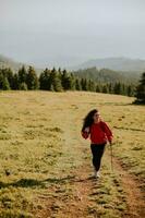 Jeune femme en marchant avec sac à dos plus de vert collines photo