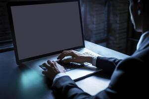 fermer vue de Jeune homme d'affaire travail sur portable et asseoir à bureau dans foncé chambre. génératif ai illustration. photo