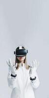portrait de Jeune femelle portant virtuel réalité casque et sécurité gants sur gris arrière-plan, génératif ai. photo
