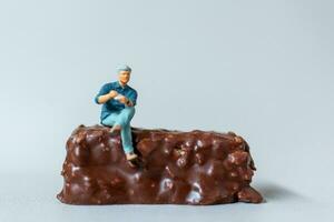 affaires homme séance sur Chocolat bars avec gris Contexte. monde Chocolat journée concept photo