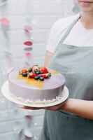 une magnifique mousse gâteau dans le mains de une Pâtisserie chef photo