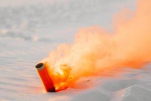 bombe fumigène avec de la fumée orange coincée dans le sable photo