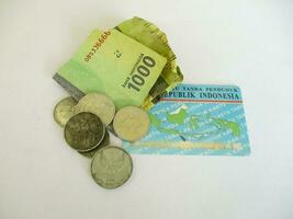 un mille Rupiah pièce de monnaie et billet de banque avec indonésien identité carte, isolé sur blanc Contexte. représentant peu argent ou manquer de de argent photo