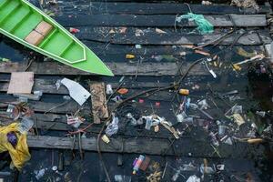 sélectif concentrer sur une vert navire cette est penché sur une sale Dock avec Ménage Plastique déchets photo