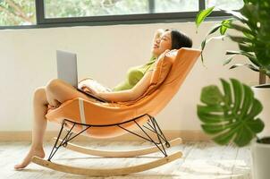 image de asiatique fille relaxant sur une chaise à sa maison photo