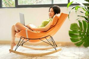 image de asiatique fille relaxant sur une chaise à sa maison photo