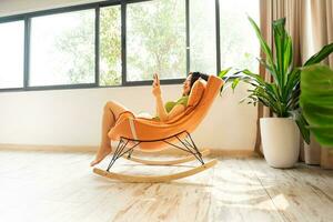 image de asiatique fille relaxant sur une chaise à sa maison photo