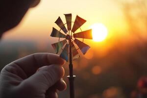 jouet Moulin à vent dans main contre une magnifique le coucher du soleil ai généré photo