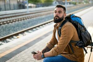 adulte homme est permanent à chemin de fer station et attendre pour arrivée de train. photo